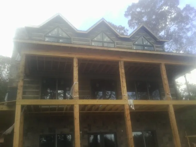 Dormers and porch framing on a large log home under construction — Roof Coating work by our crew in Minneapolis