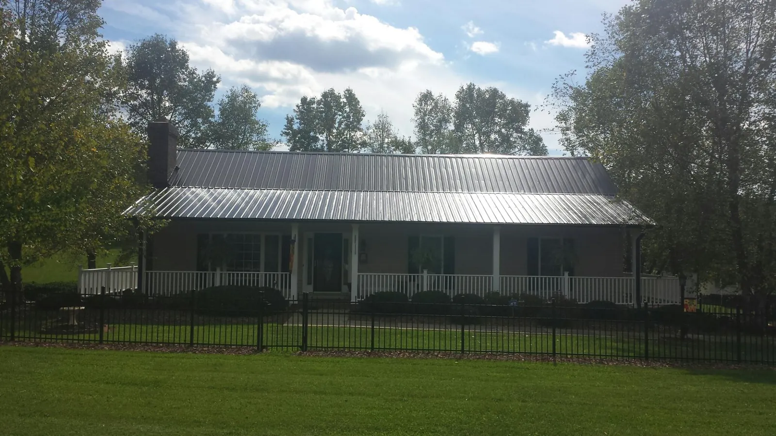Gray metal roof on a brick ranch with a full width front porch — Gutter Guard Installation work by our crew in Minneapolis